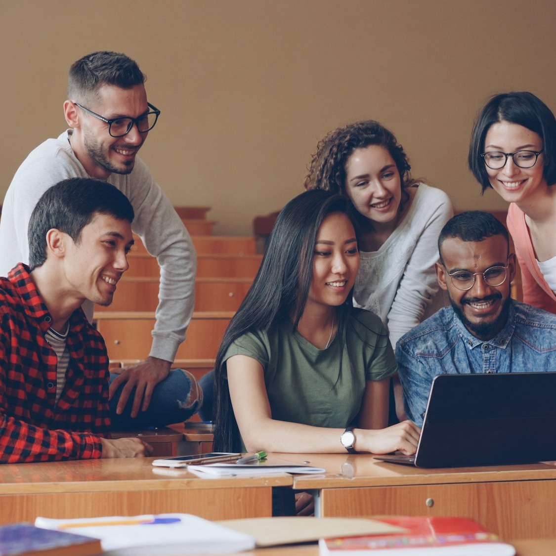 Diverse group of young professionals collaborating around a laptop.